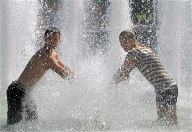 Young people enjoy water jets cooling themselves in a fountain outside the Kremlin in Moscow, Russia, Thursday, July 15, 2010. A heat wave hit central Russia breaking temperature records going higher than 30 C (86 F) for at least two weeks. (AP Photo/Mikhail Metzel)